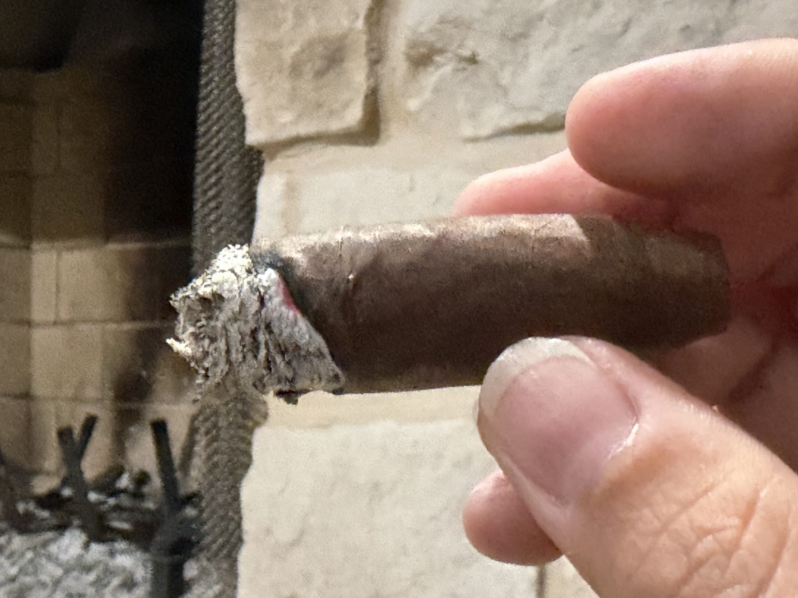 Close-up of the Aging Room Quattro Nicaragua Maestro late in the final third with both bands off, a single finger of burn running up one side of the foot while the rest of the ash sits short of it