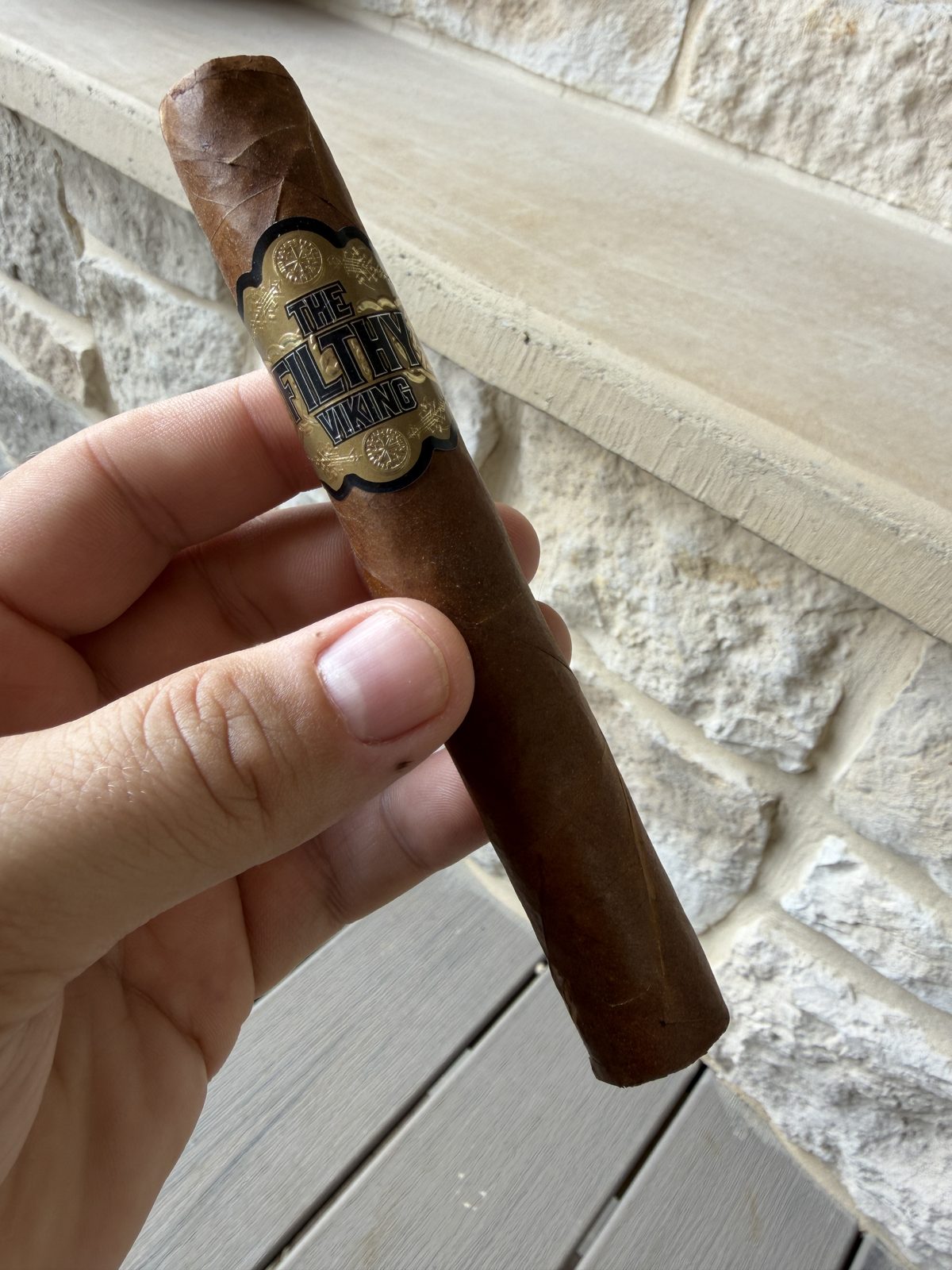 The Filthy Viking Toro held in hand before lighting, black and gold band, medium brown wrapper