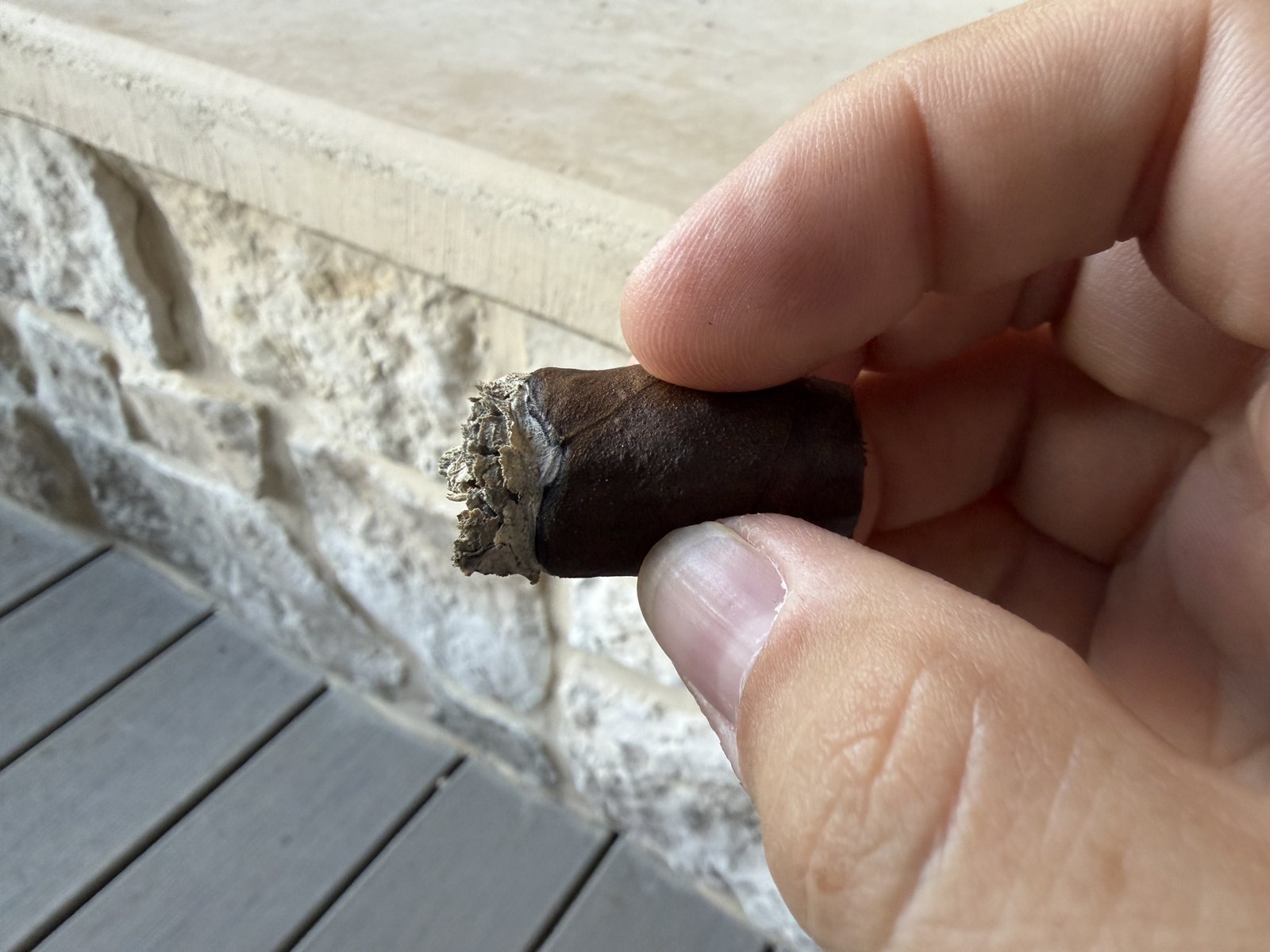 The nub of the Añejo Shark held between two fingers right before going in the ashtray