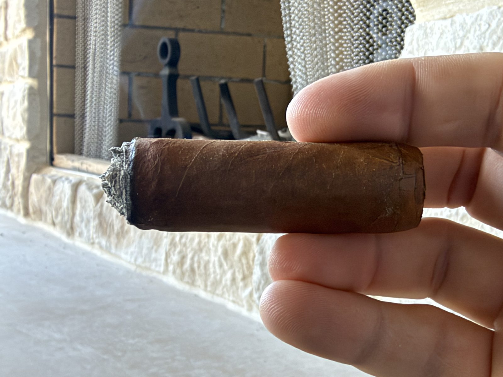 Crowned Heads Mil Días Sublime with the band removed, going into the final third, with a short gray ash on the foot
