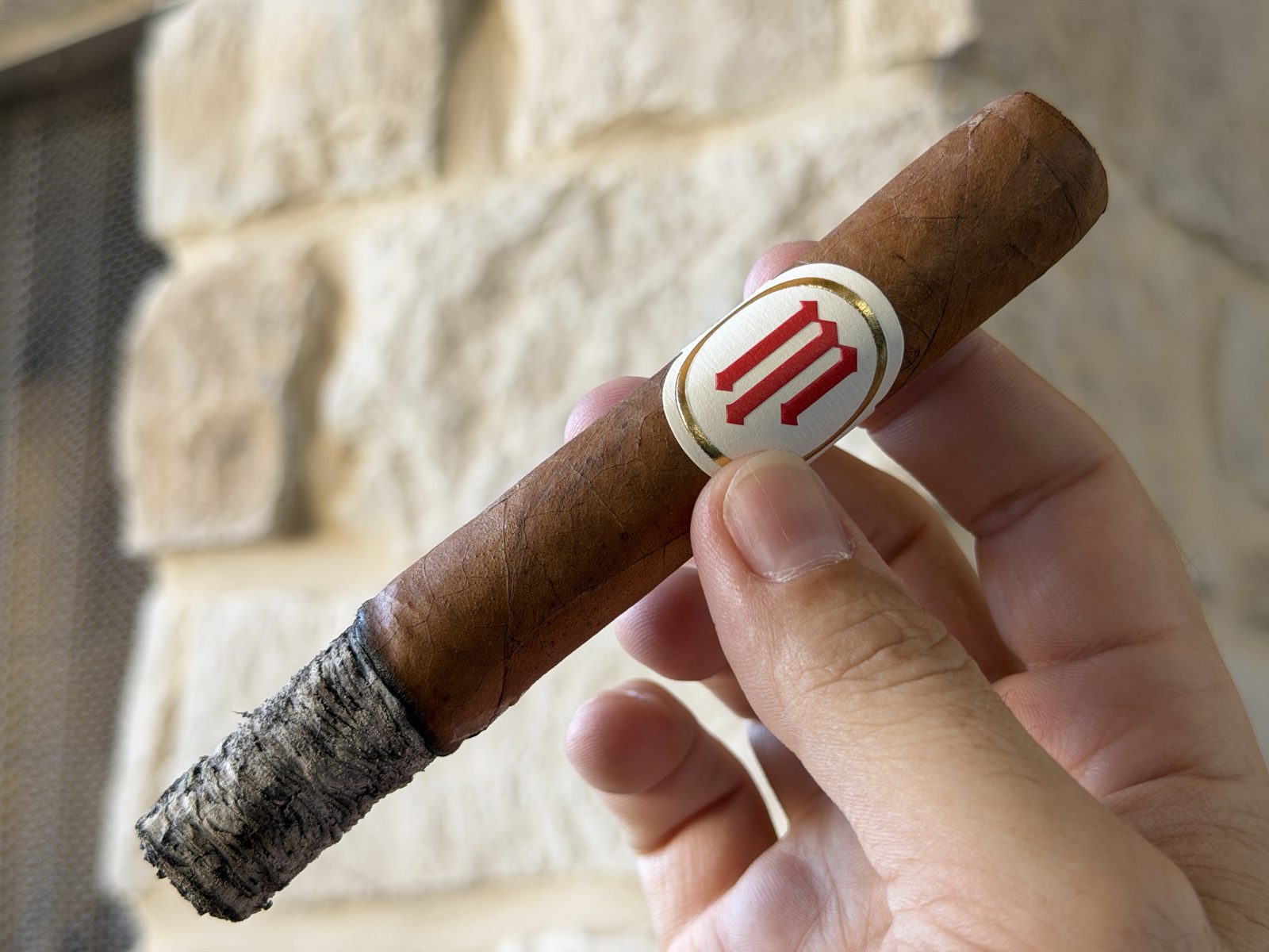 Crowned Heads Mil Días Sublime near the end of the first third, band still on, with a long tight gray ash on the foot