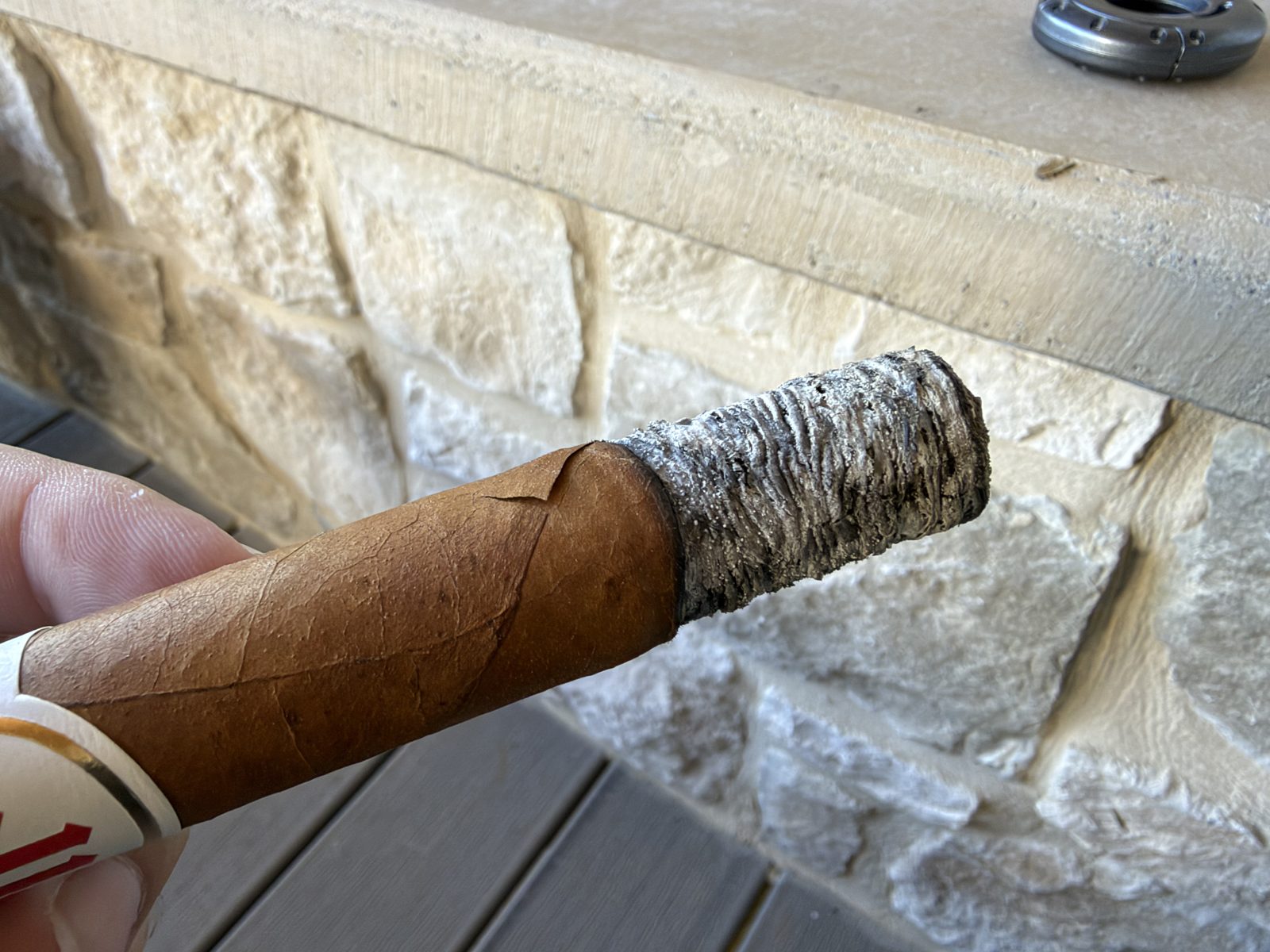 Close up of the Crowned Heads Mil Días Sublime burning in the first third, tight gray ash, with a glued crack in the wrapper visible just above the burn line