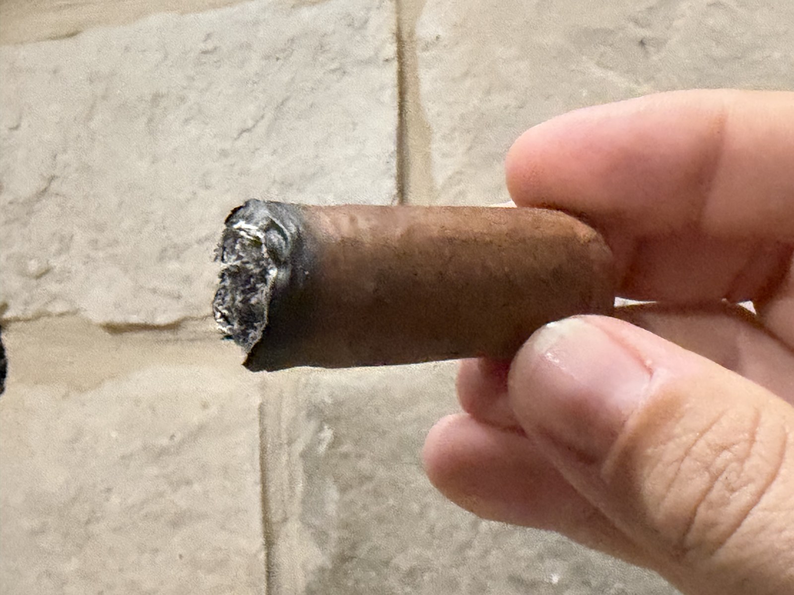The last two inches of the Crux Epicure Habano Toro with the band off, ember burning flat straight across instead of in a cone
