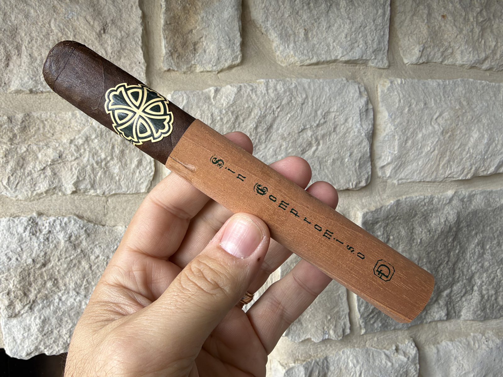 Dunbarton Sin Compromiso Seleccion No. 7 in hand with its cedar sleeve covering the lower two thirds, the sleeve stamped Sin Compromiso, and the Dunbarton cross band above it