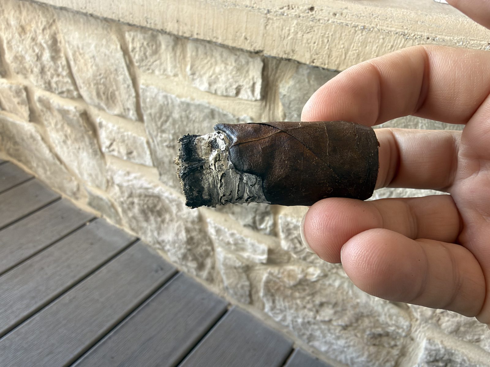 The last few inches of the Dunbarton Sin Compromiso Seleccion No. 7 held in hand with the band off, a ragged dark foot and a wavy burn