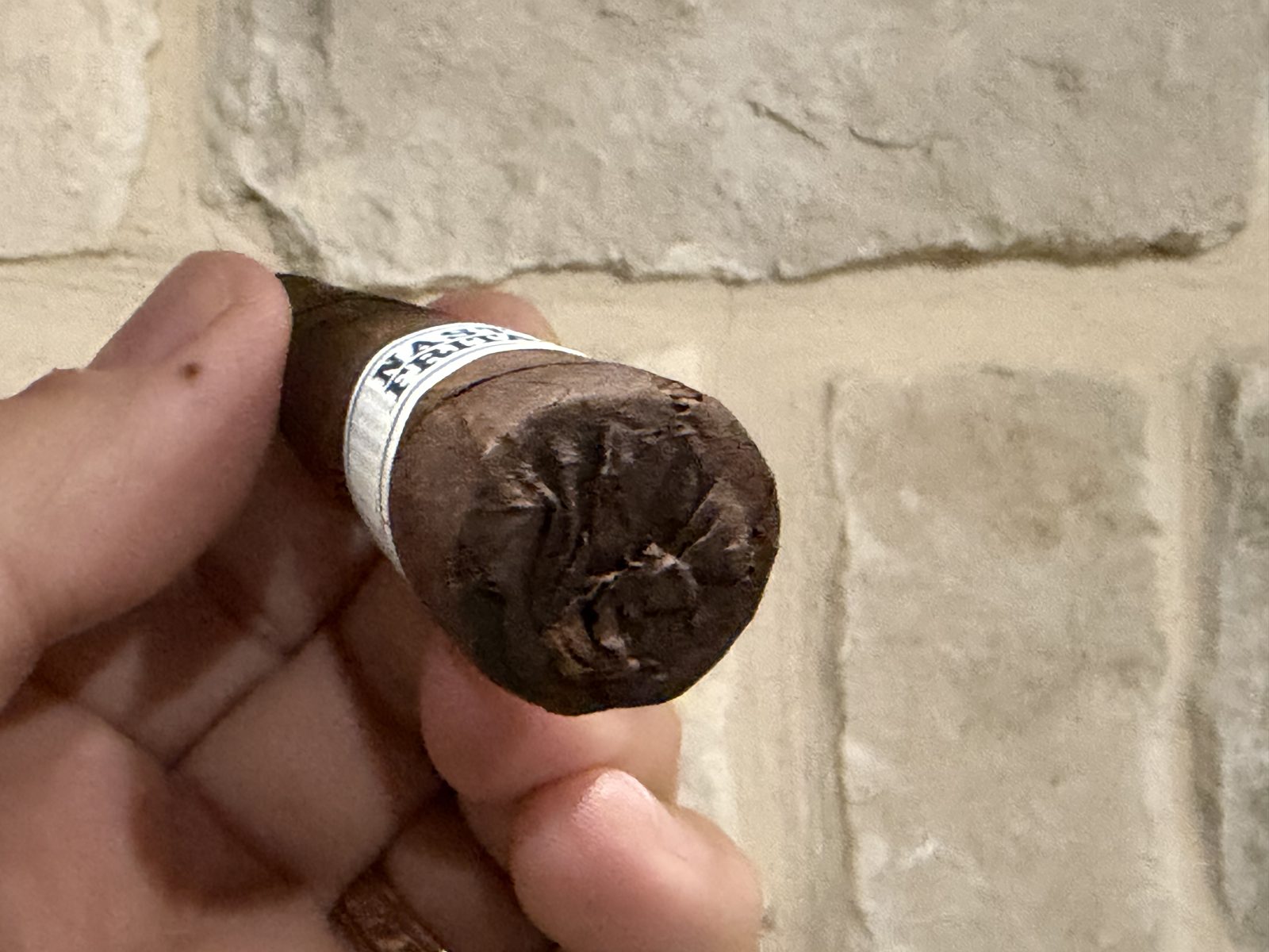 Close-up of the closed foot of the Liga Privada Unico Serie Nasty Fritas, the dark wrapper folded over the end, band just behind it