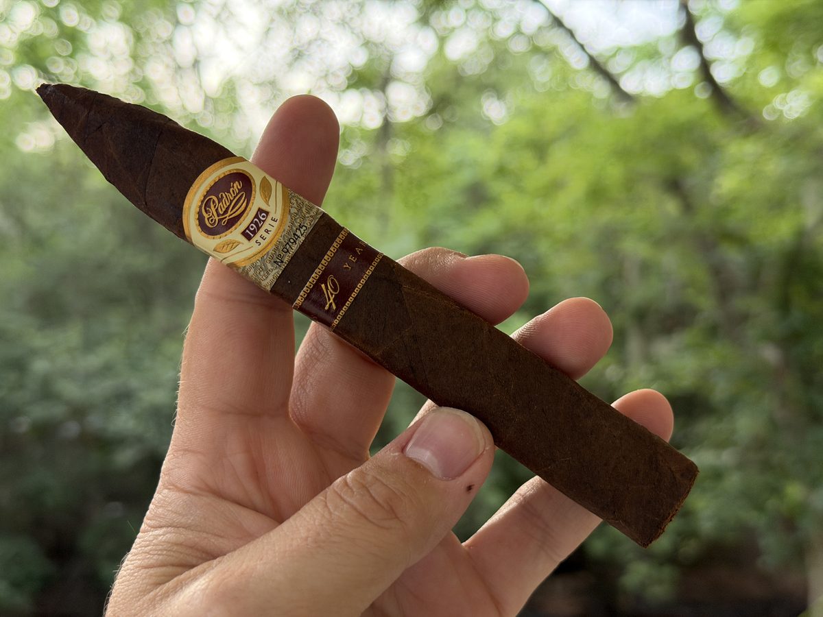 Padrón 1926 Serie 40th Anniversary Maduro box-pressed torpedo held in hand before lighting, dark oily maduro wrapper with the 1926 Serie band and 40 Years band