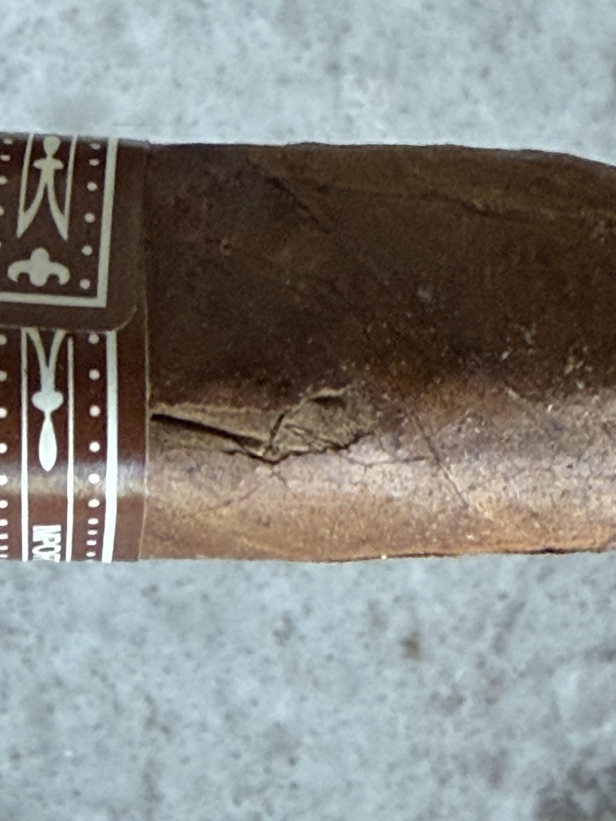 Close-up of the cracked wrapper on the Padrón 2000 Maduro near the band, outer wrapper layer torn
