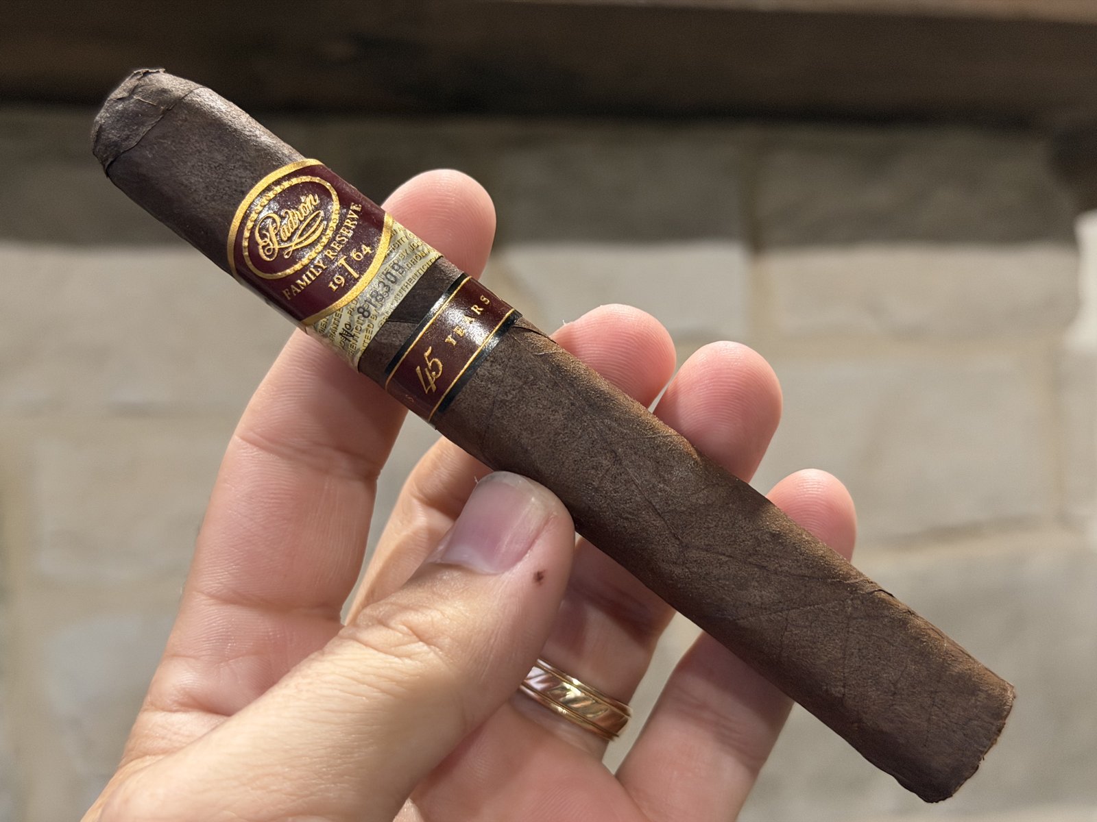 Padrón Family Reserve No. 45 Maduro box-pressed toro held in hand before lighting, dark rustic maduro wrapper with the Family Reserve 1964 band and the 45 Years band