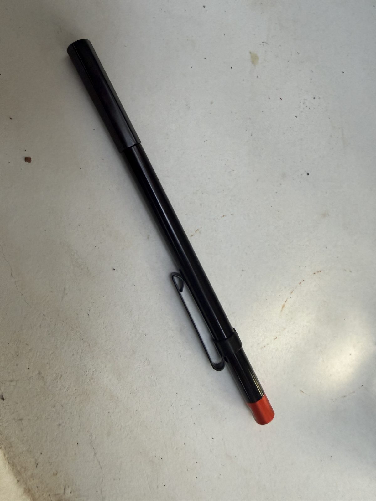 PerfecDraw cigar draw tool capped and closed, black anodized body with a red end cap and a pocket clip, looking like a slim pen