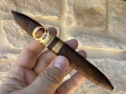 Padrón 1926 Serie 80 Years Maduro perfecto held in hand before lighting, dark toothy maduro wrapper with the 1926 Serie band and the 80 Years band