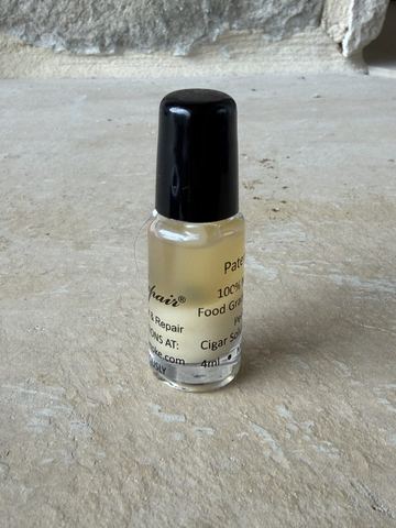 PerfecRepair cigar glue, small 4ml glass bottle with black brush cap, on a stone hearth
