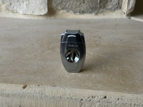 Xikar VX2 V-cut cutter closed, silver body with the polished V-cut bowl, standing on a stone hearth